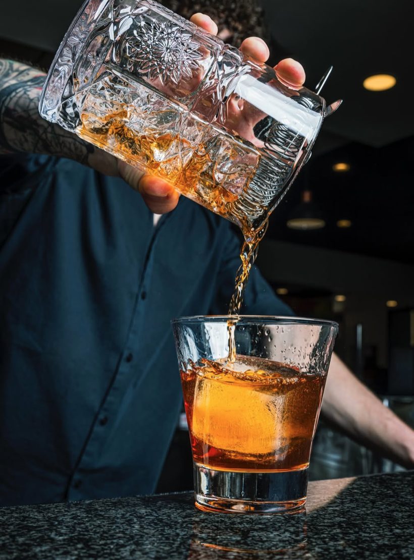 Bartender pouring a craft old fashioned at an Oakmont event