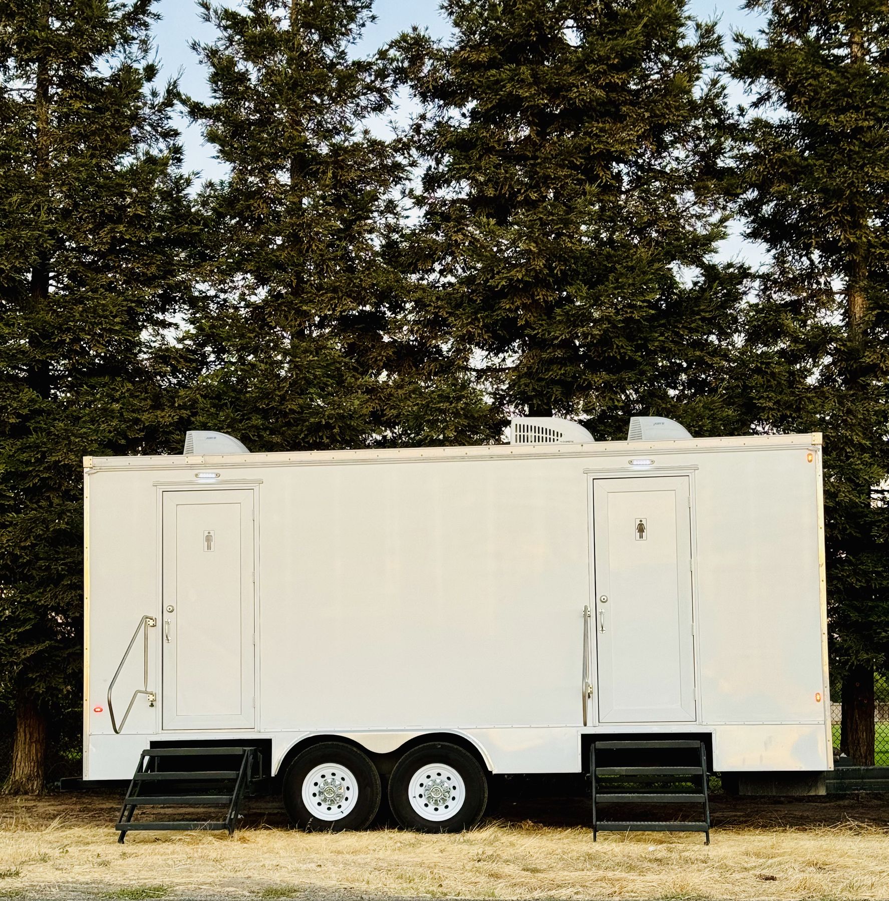 Oakmont luxury restroom trailer set up at an outdoor event among trees